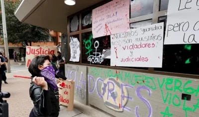 Una mujer lanza pintura sobre las paredes de un Comando de Atención Inmediata (CAI) de la Policía.