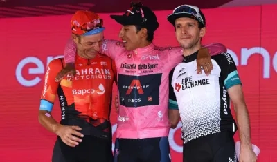 Egan Bernal celebra en el podio al lado de Damiano Caruso y Simon Yates. 