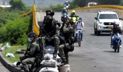 Policías vigilan la vía "Paso del Comercio", recientemente desbloqueada en Cali.