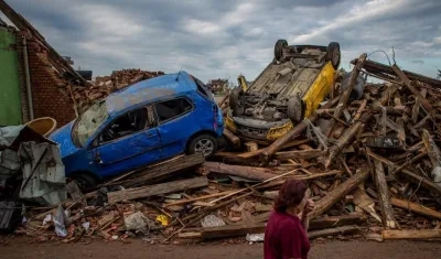Una mujer pasa junto a automóviles dañados por el tornado Mikulcice, República Checa.