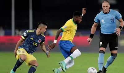 Rafael Santos Borré, delantero colombiano, marca a Fred ante la mirada de Néstor Pitana. 