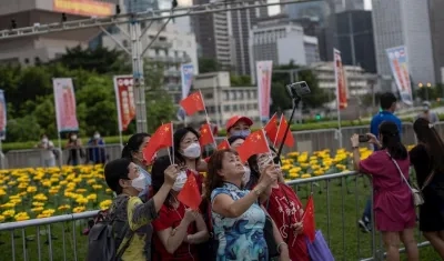 Un grupo de mujeres se toma fotografías mientras sujetan banderas chinas en Hong Kong, China. 