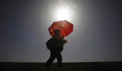 Una mujer camina resguardándose del sol con una sombrilla, en Córdoba, ayer. 