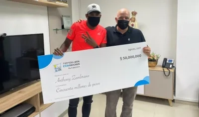 Anthony Zambrano recibe el cheque de manos de Christian Daes. 