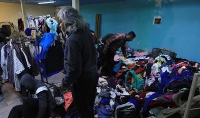 Un grupo de migrantes venezolanos selecciona ropa donada.