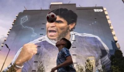 Niño juega con el balón, frente al mural de Diego Maradona. 