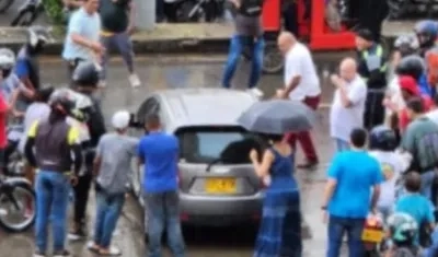 Curiosos rodean el vehículo en el que se desplazaba la mujer baleada.