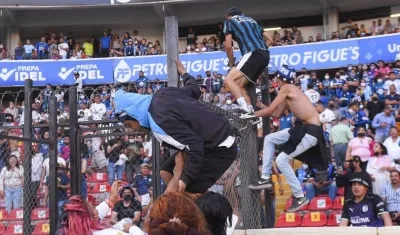 Hinchas del Querétaro se vuelan la cerca que separa la tribuna de la cancha.