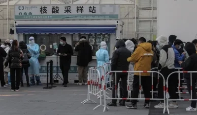Numerosas personas, protegidas con mascarillas, hacen cola para que les realicen test de antígenos y descartar que sufran de COVID-19 en Pekín, China, en una foto de archivo. 