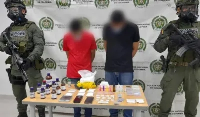 Los dos capturados y parte de las drogas incautadas.