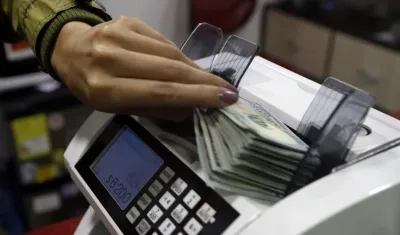 Una mujer coloca dólares en una máquina contadora de billetes en una casa de cambio de divisas, en Bogotá.