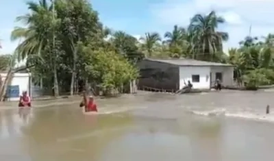 Damnificados caminan entre el agua desbordada en Santa Rosa, Pinillos