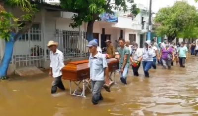 Con los zapatos en sus manos, familiares de la anciana de 90 años cargan su ataúd en La Mojana.