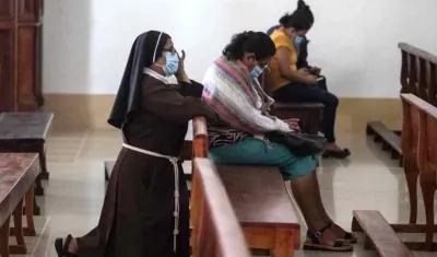 Una monja y dos feligreses orando por la suerte de los jerarcas detenidos.