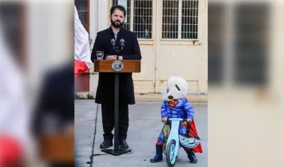 Gabriel Boric en pleno discurso. El niño disfrazado se detiene para observarlo.