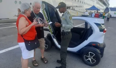 Un policía atiende a dos turistas que arribaron en un crucero a Cartagena.
