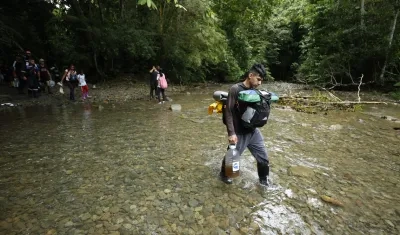 Migrantes cruzan un río en el Tapón del Daríen.