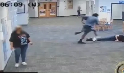 La maestra yace inconsciente el suelo, pero el estudiante la sigue pateando.