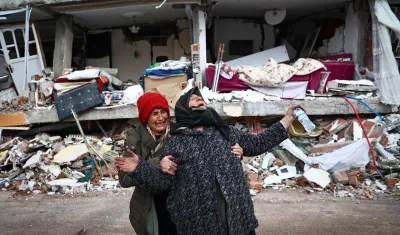 Dos mujeres lloran junto a un edificio derrumbado tras el gran terremoto en el distrito de Elbistan de Kahramanmaras.