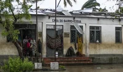 Varias personas se protegen de la lluvia en una calle inundada tras de la destrucción causada por el ciclón Freddy en Quelimane, Mozambique.