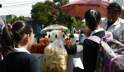 Unas niñas estudiantes compran frituras afuera de un colegio en Ciudad de México