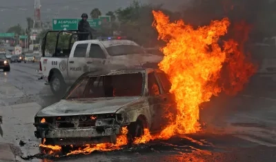 Personal de la policía estatal resguardan la zona donde un vehículo de alquiler fue incendiado. 