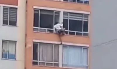 Mujer intentando salir por la ventana de su casa.