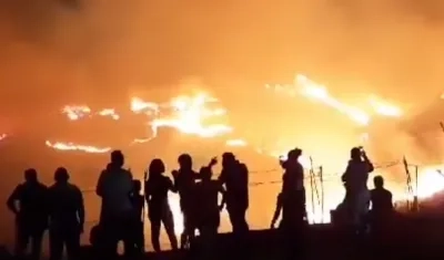 Personas observan las llamas que han arrasado 60 hectáreas de material vegetal en Cali