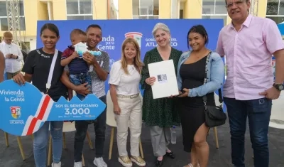 Gobernadora entregando título de propiedad a una familia beneficiada. Ministra de Vivienda estuvo presente.