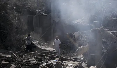 Dos palestinos miran los escombros de la casa destruida de la familia Al Shawa, en Gaza.