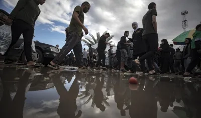 Los palestinos pasan junto a un charco de agua después de una noche lluviosa.