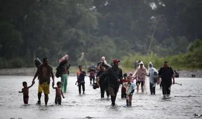 Migrantes cruzan el río Turquesa, en Darién (Panamá).