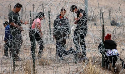 Migrantes intentan cruzar la cerca de alambres en la frontera que divide a México de los Estados Unidos. 