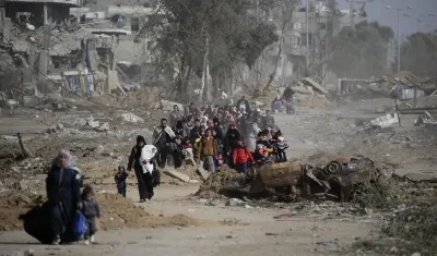 Palestinos caminan después de cruzar desde el norte de la Franja de Gaza mientras los tanques israelíes avanzan a lo largo de la carretera Salah Al Din, en el centro de la zona