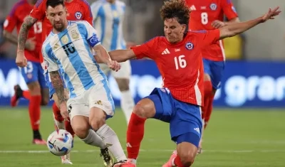 Lionel Messi disputa el balón con el chileno Igor Lichnovsky.