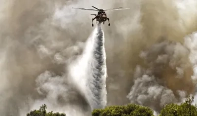 Un helicóptero de extinción de incendios arroja agua durante un incendio forestal. 