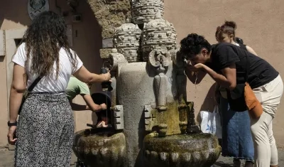 Varias personas se refrescan en una fuente en Roma, Italia.