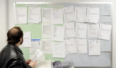 Un hombre buscando trabajando en tablón de anuncios de un centro de desempleo.