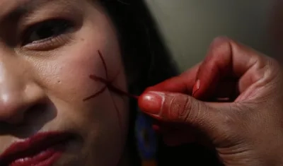 Una mujer indígena se pinta el rostro durante la inauguración de la Zona Verde de la COP16 en Cali.