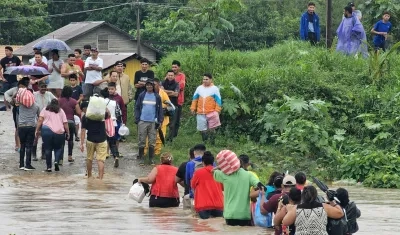 Comunidad cruzando con sus pertenencias por un río en medio de las inundaciones.