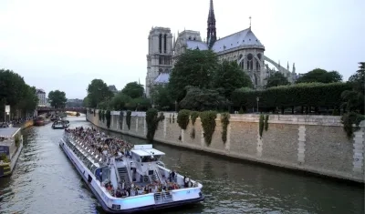 Un barco con turistas navegando por el Sena junto a la catedral de Notre Dame.