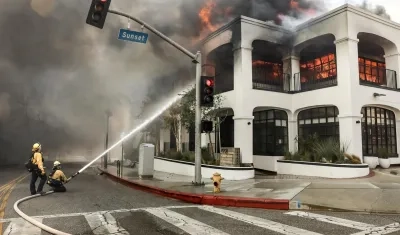 Los bomberos luchan contra las llamas que envuelven un edificio durante el incendio forestal de Palisades. 