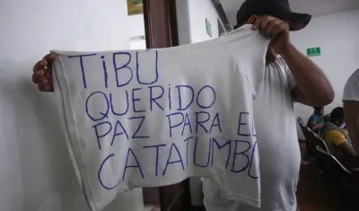 Un hombre desplazado por la violencia muestra una camiseta que pide paz para el Catatumbo.