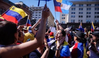 Personas agitan la bandera de Venezuela y gritan consignas este sábado en al Plaza de Mayo.