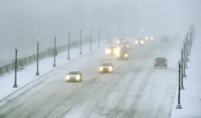 Vehículos avanzando en medio de la nieve en el Puente Memorial de Arlington que conecta a Virginia con Washington.