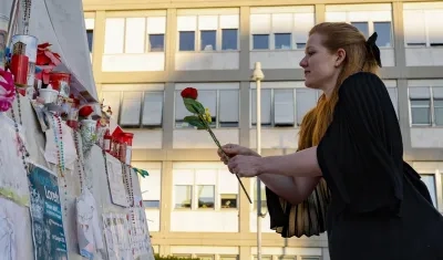 Una mujer coloca una flor frente a la estatua de Juan Pablo II en la entrada del Hospital Gemelli.