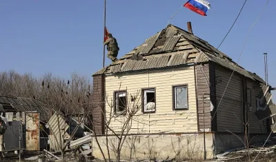 Un soldado ruso instalando una bandera roja en el techo.