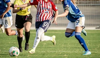 Wesly Rodríguez avanza con la marca de una jugadora de Millonarios.