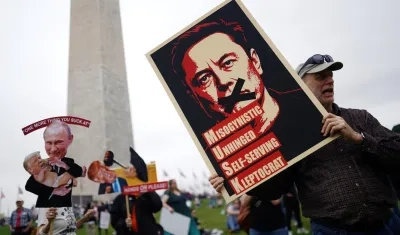 Un manifestante sostiene un cartel que representa a Elon Musk con el texto '¡Manos afuera!' en el National Mall en Washington.