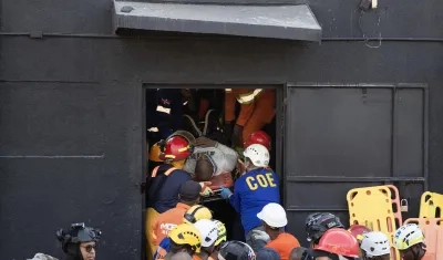 Integrantes del cuerpo de bomberos y de rescate evacuan a un herido este martes, en la discoteca Jet Set en Santo Domingo.